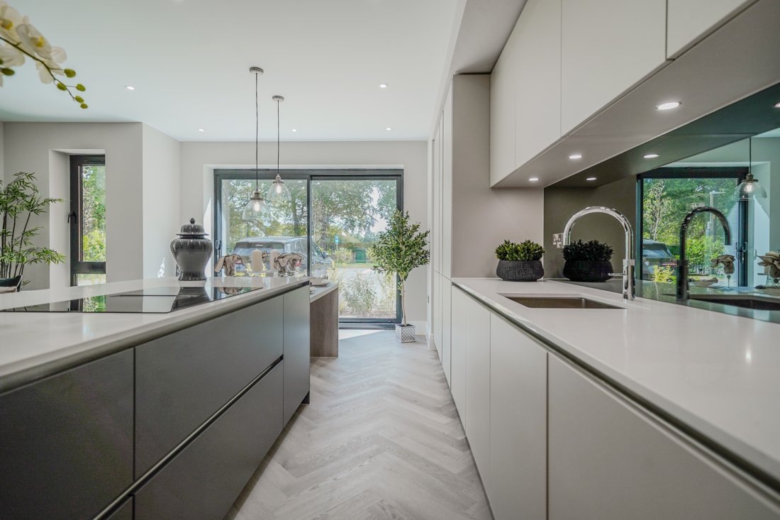 Interior of a previous HCD home — a finely appointed kitchen with herringbone flooring and garden views